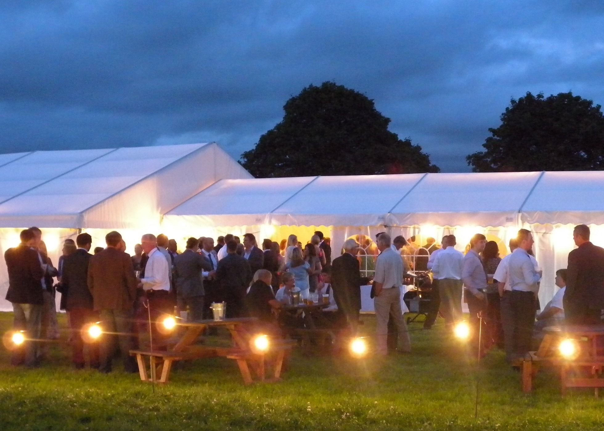 exterior view of marquee at night showing people mingling outside and festoon lighting