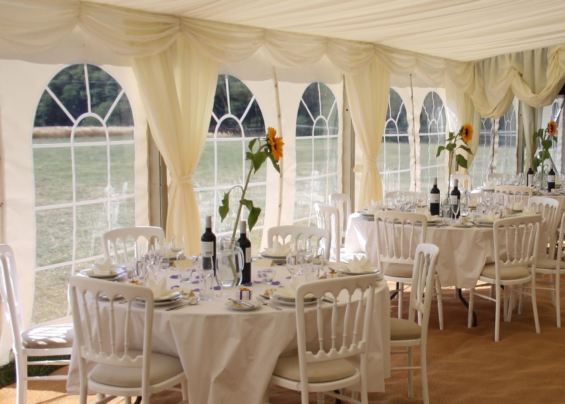 interior view of wedding marquee with sunflower table centres and white cheltenham chairs